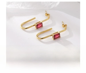Detail view of U-shaped gold-plated titanium earrings with rectangular red zircon stone