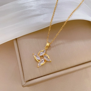 Rotating crystal clover pendant on gold titanium chain displayed on a jewelry box