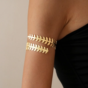 Macro detail of golden laurel leaf arm cuff showing metallic texture and leaf patterns
