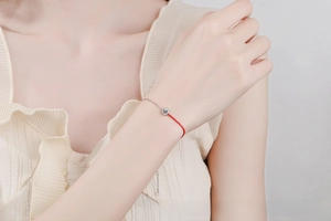Detail of red string and S925 silver chain bracelet with a sparkling moissanite stone