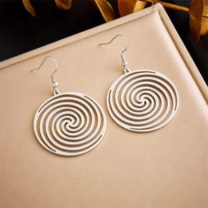 Macro shot of silver spiral hollow earrings with fishhook clasp on leather texture