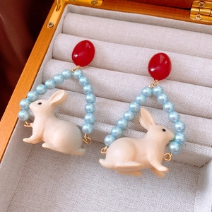 Detail of bunny pendant earrings with pearl beads in a velvet jewelry display box