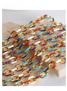 Detail of colorful enamel gold chain links in red, blue, and purple on stone background