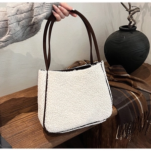 Detail of white faux fur tote bag with brown leather trim and retro shoulder strap