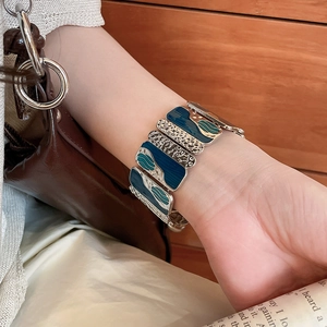 Detailed shot of a wide silver hammer-textured enamel cuff bracelet on a model wrist