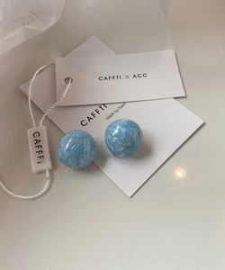Gros plan de boucles d'oreilles boules bleu clair avec texture marbre blanc sur carte