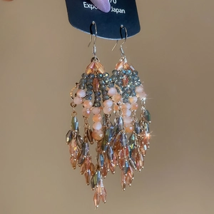 Detail of beaded tassel earrings with champagne crystals and leaf accents in boho style