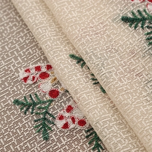 Close-up of beige Christmas tablecloth with red cane embroidery and woven texture