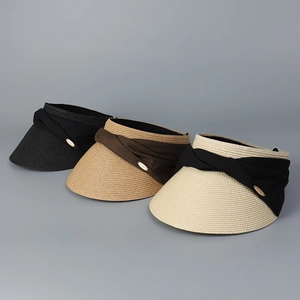 Detailed close-up of woven sun hats in black, brown, and beige with fabric knot decor