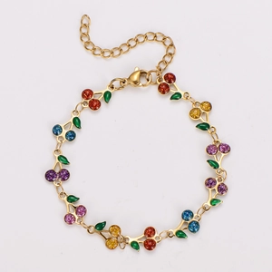 Detail of bohemian gold cherry bracelet with colorful gemstone fruit and green enamel leaves