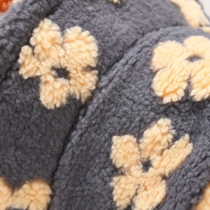 Macro view of dark grey lamb wool texture with yellow floral patterns on the fisherman hat