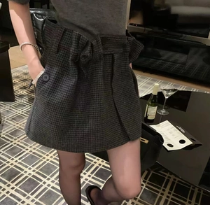 Detail view of high waist plaid wool skirt with pocket and pleated dark tweed pattern