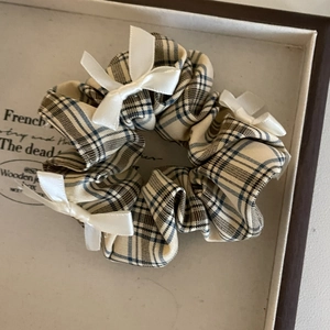 Detail of warm coffee plaid scrunchie with multiple white silk bows on light background