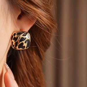 Gros plan de boucles d'oreilles carrées motif léopard portées par un mannequin