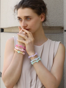 Close-up of stacked jelly star bracelets in macaron colors worn on model's wrist