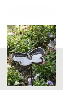Makro-Detail des antiken Vogelfutterspenders aus Gusseisen mit Schmetterlingsflügeln und Vogel