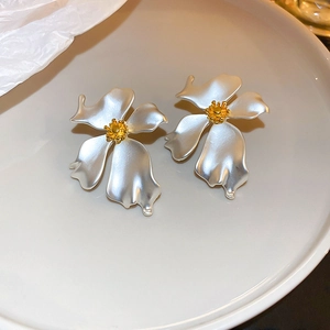 Detailed view of silver flower earrings with gold center on a white tray