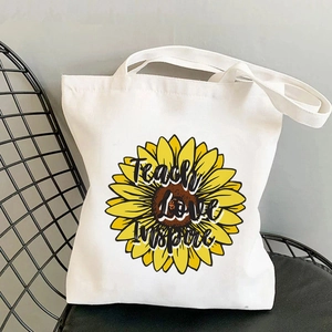 Off-white canvas tote bag with Teach Love Inspire sunflower print on a black chair