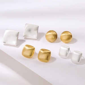 Minimalist geometric stud earrings in gold and silver with a brushed metal texture