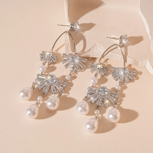 Elegante Silberohrringe mit Zirkonia-Blumen und Perlen auf warmem, minimalistischem Grund
