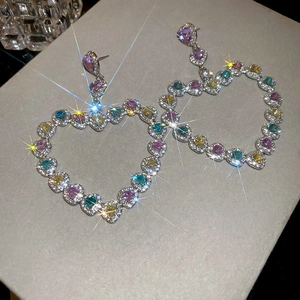 Détail macro de boucles d'oreilles cœur en argent avec zircons multicolores