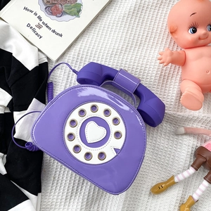 Detailed flat lay of a vintage purple telephone-shaped shoulder bag made of patent leather