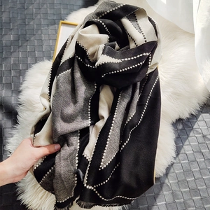 Detail of soft cashmere-feel scarf featuring black and white geometric wave patterns