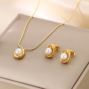 Macro shot of gold-plated jewelry set with white pearls on a soft silk background