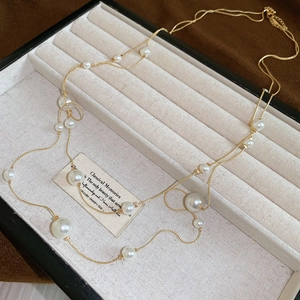 Elegant double-layer gold chain necklace with round white pearls on a jewelry display