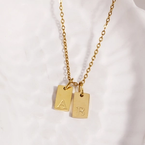 Close-up of golden stainless steel square pendants with A and B letter engravings