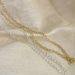 Detailed macro view of gold and silver sterling silver O-chain necklaces on fabric
