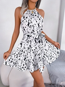 Detail of a white leopard print halter dress featuring a ruffled hem and waist tie belt