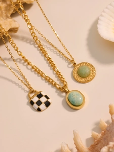 Detail of gold necklaces with green turquoise and checkerboard pendants on seashell