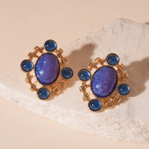 Macro shot of vintage gold drop oil earrings with purple and blue stones on stone