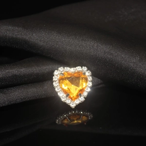 Macro view of heart-shaped orange crystal ring with white diamond border on black silk