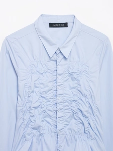 Détail macro de la chemise en popeline bleu clair avec plis fins et boutons blancs