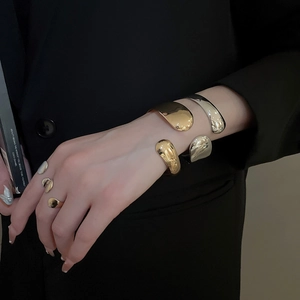 Polished liquid metal bracelets and rings set on model with minimalist aesthetic