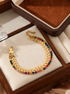Macro shot of double-layered gold chain bracelet featuring colorful rhinestones and V-shapes
