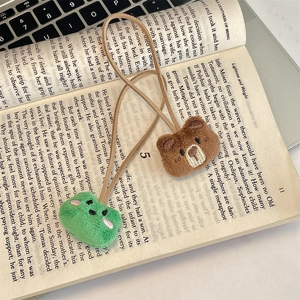 Close-up of plush bear and frog hair ties on an open book showing detailed embroidery