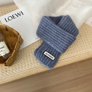 Detail shot of a blue thick knit scarf with ribbed texture and woven brand label