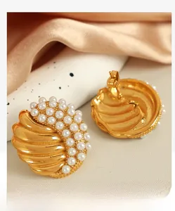 Detail of gold shell texture earrings with inlaid white pearls in French retro style