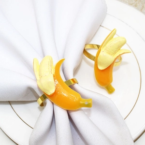 Close-up of yellow peeled banana napkin rings on white napkins and gold-rimmed plate