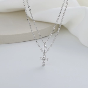 Macro detail of silver double-layer necklace with cross pendant and marquise zircon