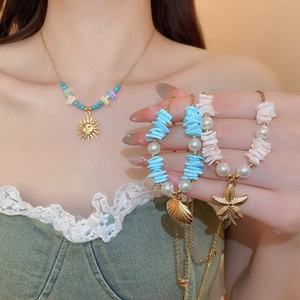 Macro detail of starfish and seashell charms on gold necklaces with colorful beads