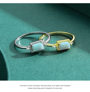 Detailed close-up of gold and silver S925 opal rings with diamond accents on dark green paper
