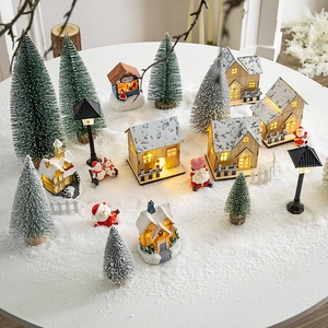 Lighted wooden Christmas village house set with mini trees and Santa figurines on snow