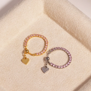 Detail of adjustable pink zircon rings in gold and silver with heart-shaped charms