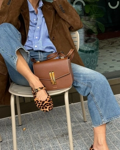 Detail of burgundy suede jacket paired with a brown leather shoulder bag and leopard flats