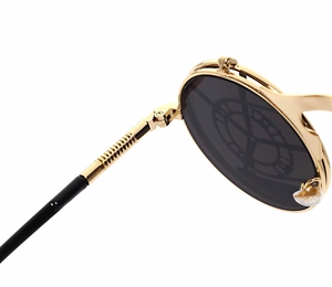 Detail of gold metal punk sunglasses with spring hinges and Saturn orb pattern lens