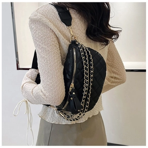 Close-up of quilted black waist bag featuring gold chains and adjustable strap on a model